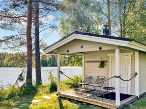A small wooden cabin with a porch, two chairs, and a table. - Villa rauha by Interhome (Soini)