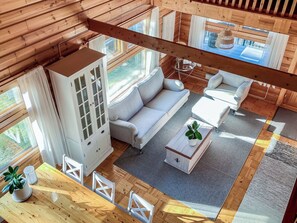 A cozy cabin interior with a sofa, a cabinet, and a dining table.