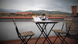 Eine Terrasse mit Tisch für zwei Personen, komplett mit einer Weinflasche, Gläsern und zwei Holzstühlen.