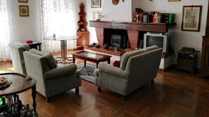 Ein Wohnzimmer mit Kamin, zwei Sesseln, einem Couchtisch und einem Fernseher.