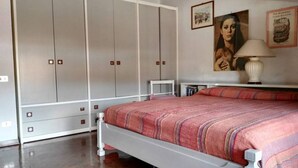Ein Schlafzimmer mit Bett, Kleiderschrank, Nachttisch und Lampe.