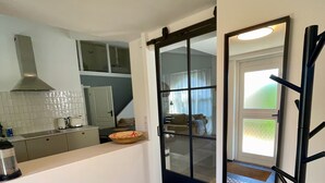 A modern kitchen with a large island, a black-framed sliding door, and patterned floor tiles.
