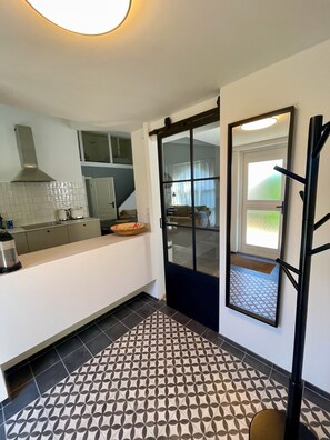Una cocina moderna con una isla grande, una puerta corredera con marco negro y baldosas de suelo con diseño.