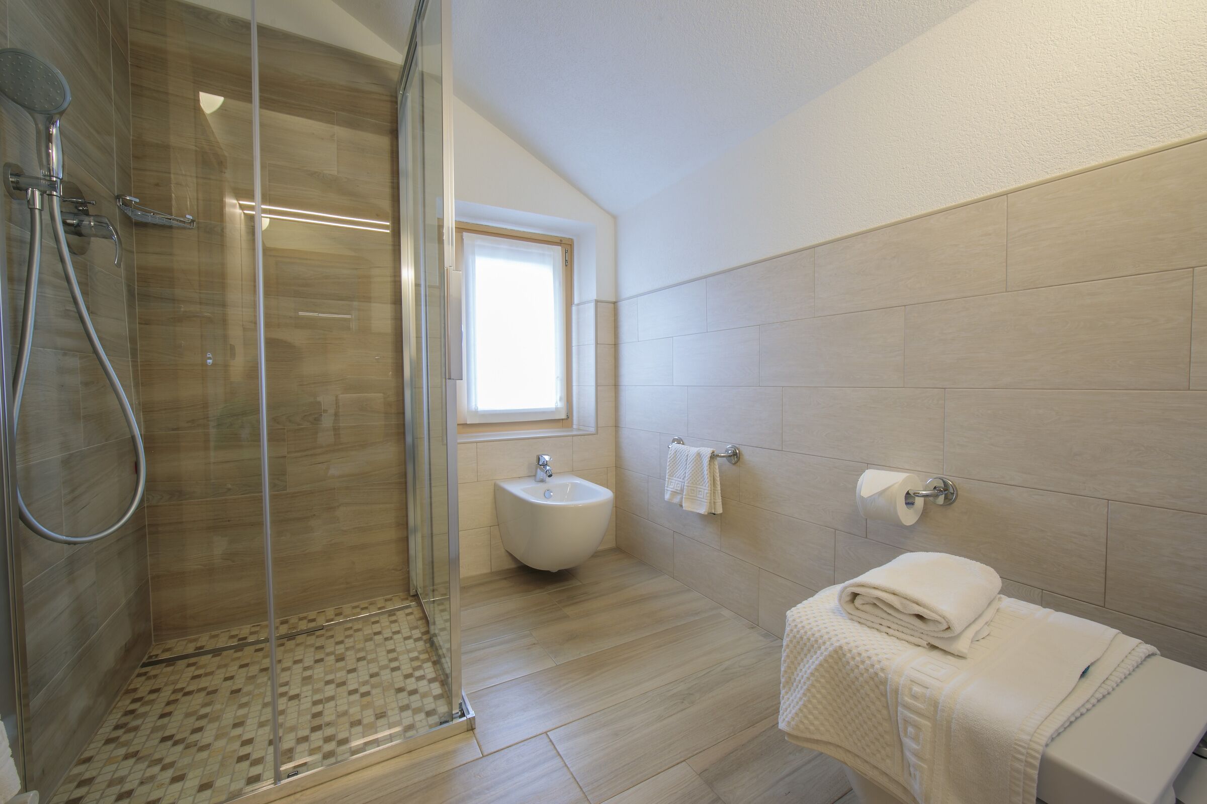 Une salle de bain moderne dotée d’une douche à parois de verre, d’un bidet et de toilettes.