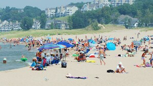 A crowded beach with people sunbathing and swimming, umbrellas, and beach chairs. - 3-bedroom vacation home - perfect for Tulip Time or Hope College Events! (Holland)