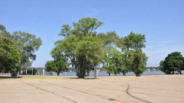 A large open parking area with trees and a lake in the background. - 3-bedroom vacation home - perfect for Tulip Time or Hope College Events! (Holland)