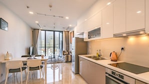 A modern kitchen with a built-in oven, a coffee maker, and a large window offering a city view. - NES House - Riverview Apartment (Ho Chi Minh City)