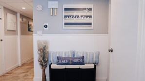 A reception area with a bench, a welcome sign, and a nautical-themed pillow.