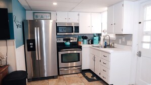 A modern kitchen with white cabinets, stainless steel appliances, and a blue accent wall.