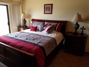 A neatly made bed with a floral bedspread, a wooden headboard, and two bedside tables with lamps and a small decorative item.
