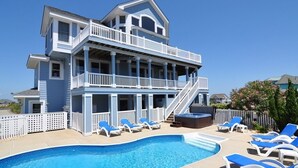 Un bâtiment à deux étages doté d’une piscine, de plusieurs balcons et de chaises longues.
