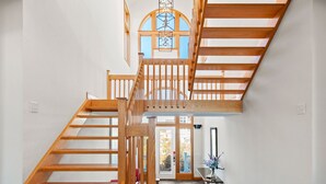 Un escalier en bois menant à l’étage supérieur, avec une lucarne au-dessus.