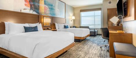 A hotel room with two beds, a desk, a chair, a large window, and a painting on the wall.