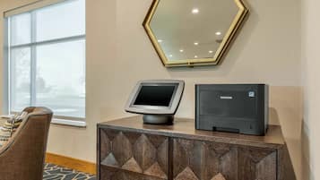 Una habitación con un amplio ventanal, un espejo en la pared, una impresora Samsung y un mueble con motivos.