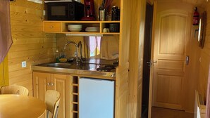 A compact kitchen with wooden cabinets, a sink, a microwave, and a refrigerator. - Belle Epoque Trailer of Saint-Pardoux 63440 2 places (Saint-Pardoux)