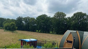 A swimming pool with a wooden deck, a small ladder, and a fenced area with a green structure in the background. - Belle Epoque Trailer of Saint-Pardoux 63440 2 places (Saint-Pardoux)