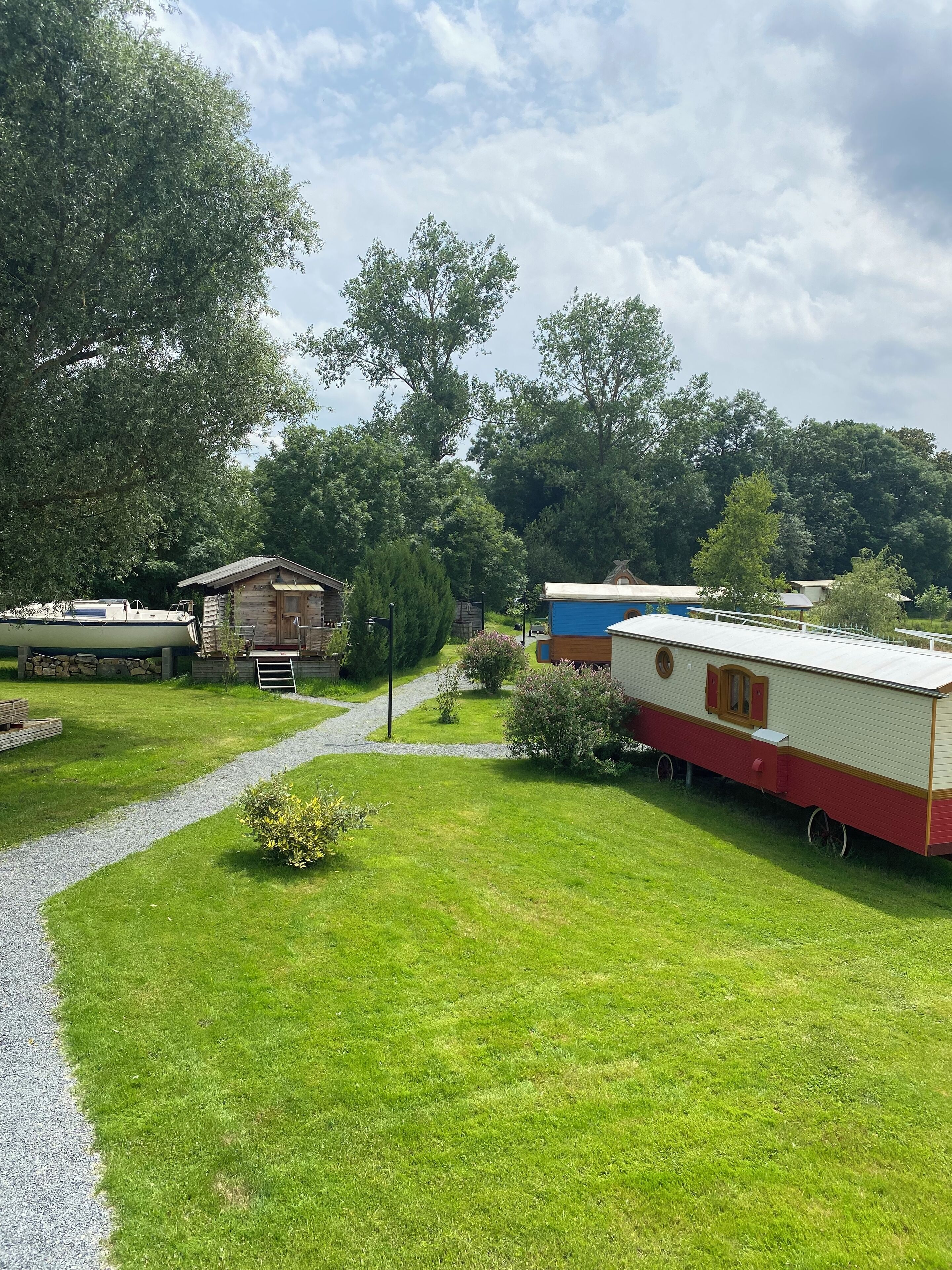 Un camping con casas móviles, un camino de grava y vegetación circundante.