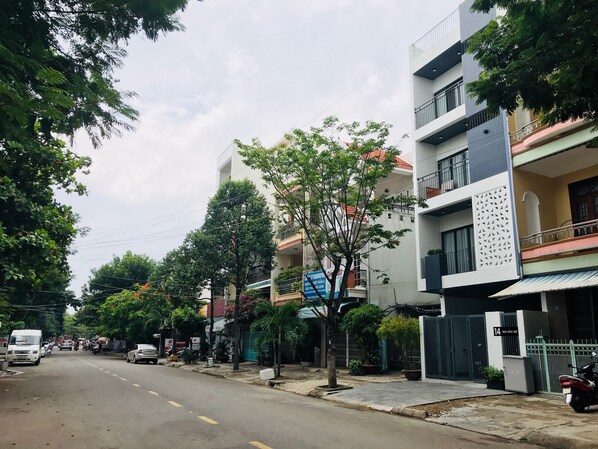 A street lined with multi-story residential buildings, some with balconies and potted plants.