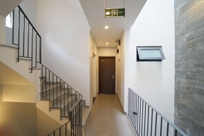 A hallway with a staircase on the left, a door at the end, and a window on the right. - Affordable and Quiet Studio near Dragon Bridge (Da Nang)