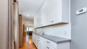Une cuisine avec des meubles blancs, un plan de travail en granit et un thermostat numérique fixé au mur.
