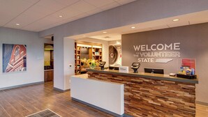 A hotel reception area with a modern design, featuring a reception desk, a welcome sign, and a view of the lobby.