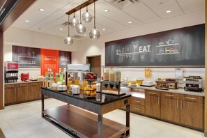 A modern kitchen area with a central island, various food items, and a chalkboard menu. - Hampton Inn & Suites Nashville North Skyline (Madison)