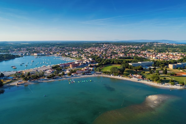An aerial view of a coastal town with a marina, residential buildings, and a beach area.