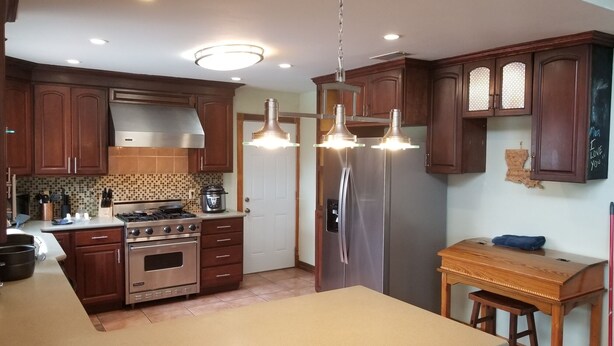 A kitchen with wooden cabinets, stainless steel appliances, and pendant lighting.