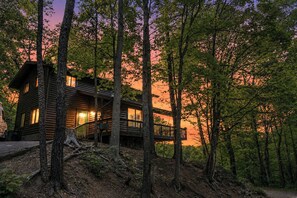 Une cabane en rondins dotée d’une terrasse, entourée d’arbres.