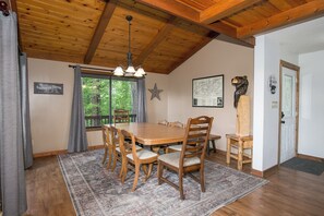 Un coin repas avec une table et des chaises en bois, un lustre, une décoration en forme d’étoile et une fenêtre avec des rideaux.