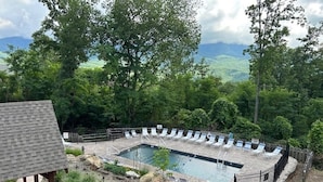 A rectangular pool with lounge chairs around it, surrounded by a stone deck and a wooden fence. - Enjoy Starry Nights, Views, Privacy & Woods- Hot Tub, Game Room, Dog-Friendly (Gatlinburg)