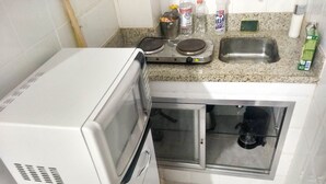 A compact kitchen with a microwave, a small sink, and a glass cabinet. - Charming studio 5 mins walk from Copacabana beach (Copacabana)