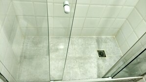 A shower with a glass door, white tiles, and a drain in the floor. - Charming studio 5 mins walk from Copacabana beach (Copacabana)