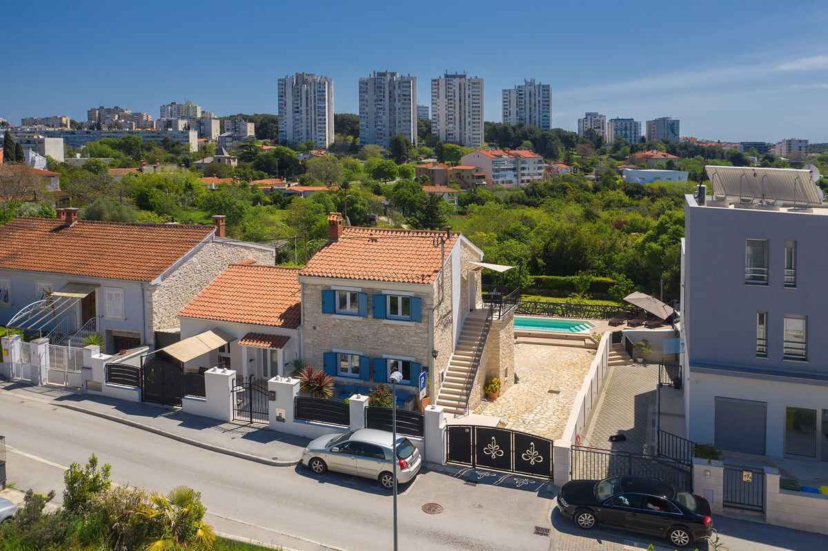 Zona residencial con una calle, coches estacionados y edificios con tejados de tejas rojas.