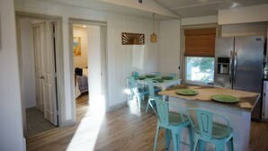 A kitchen with a central island, teal chairs, and a stainless steel refrigerator. - Fall Specials Available! Pet Friendly! Steps to white sandy beaches and the bay!  Automatic discounts applied for stays longer than 7 days and 30 days! (Bradenton Beach)