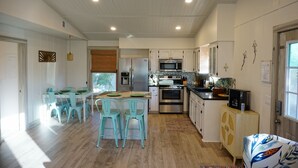 A modern kitchen with white cabinets, stainless steel appliances, and a dining area with turquoise chairs. - Fall Specials Available! Pet Friendly! Steps to white sandy beaches and the bay!  Automatic discounts applied for stays longer than 7 days and 30 days! (Bradenton Beach)