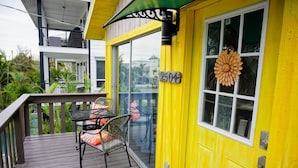 A yellow building with a balcony, a table with chairs, and a decorative item on the door. - Fall Specials Available! Pet Friendly! Steps to white sandy beaches and the bay!  Automatic discounts applied for stays longer than 7 days and 30 days! (Bradenton Beach)