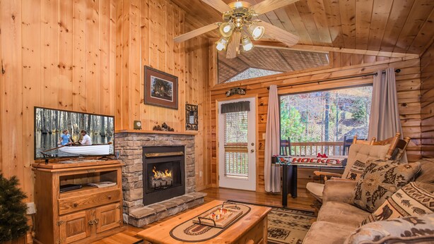Acogedor interior de cabaña de troncos con chimenea, muebles de madera y una puerta decorada con temática de hockey.