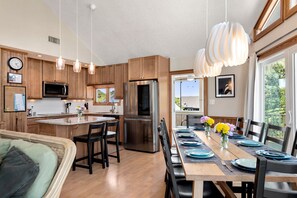 A modern kitchen with wooden cabinets, stainless steel appliances, and pendant lighting.