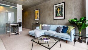 Un salon moderne avec un canap é bleu clair, une table basse en verre et une grande plante verte.
