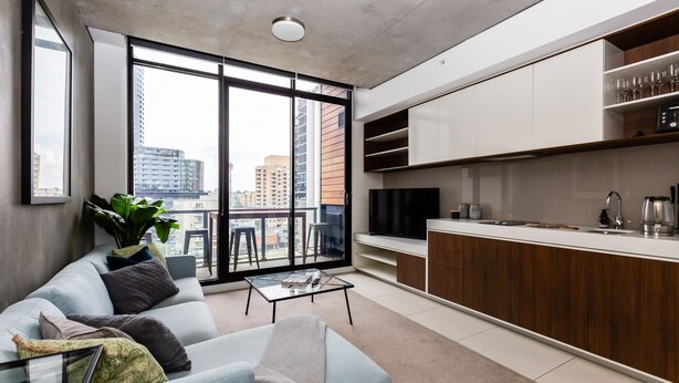 Un salon moderne avec un canapé, une table basse et une grande fenêtre donnant sur la ville.