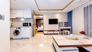 A modern hotel room with a kitchen area, a dining table, a TV, and a bed. - Hotel DK (Seogwipo)