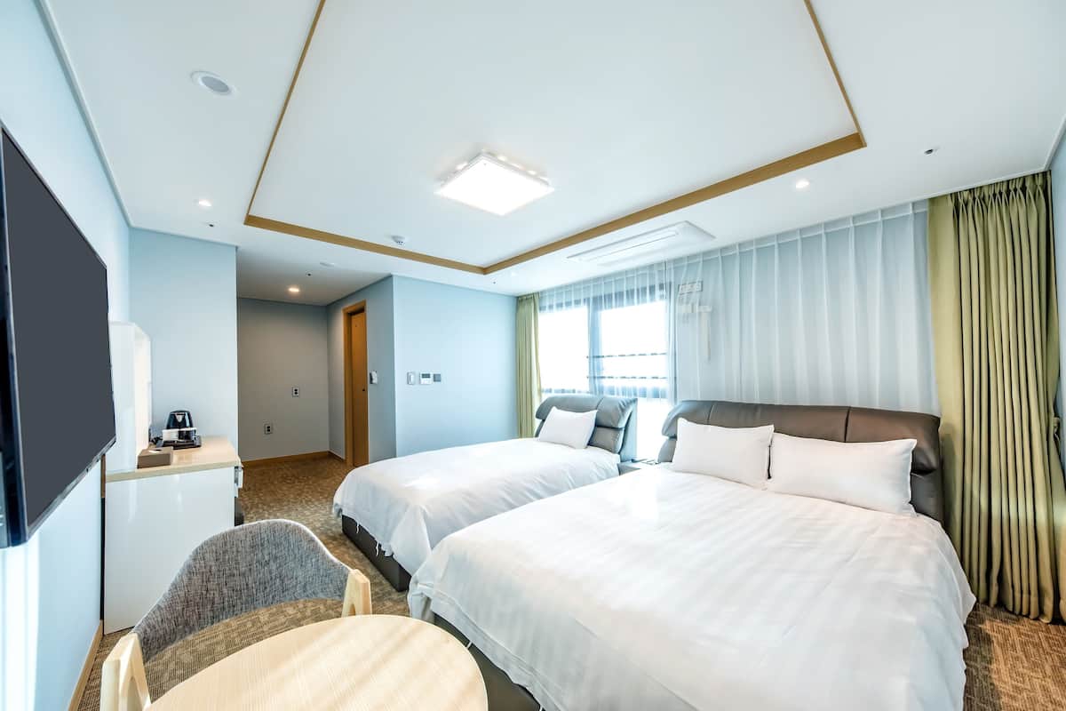Habitación de hotel con dos camas, un escritorio, una silla y una televisión.