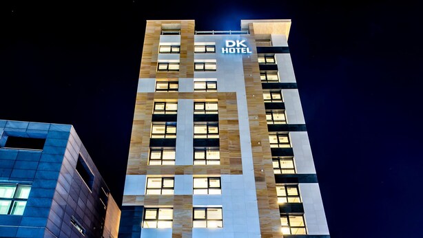 A hotel building with a sign reading "GRAND OPEN HOTEL DK" and a parking sign. - Hotel DK (Seogwipo)
