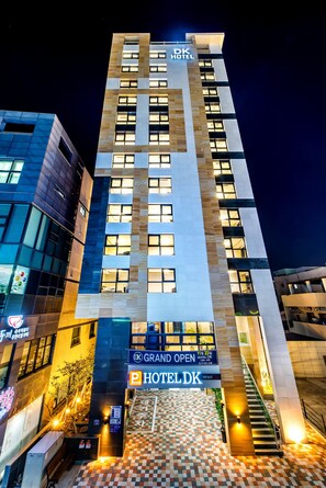 A hotel building with a sign reading "GRAND OPEN HOTEL DK" and a parking sign. - Hotel DK (Seogwipo)