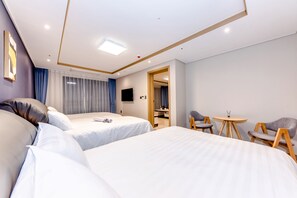 A modern hotel room with two beds, a TV, a small table, and a seating area. - Hotel DK (Seogwipo)