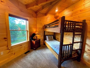 Relax in this cabin room with a bunk bed, large window, and cozy wooden decor.