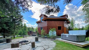 A rustic cabin with a stone patio, a hot tub, and a deck area. - Unique 'yurt' home in Bretton Woods  with hot tub, firepit, trails, beach, swimming, volleyball! (Bretton Woods)