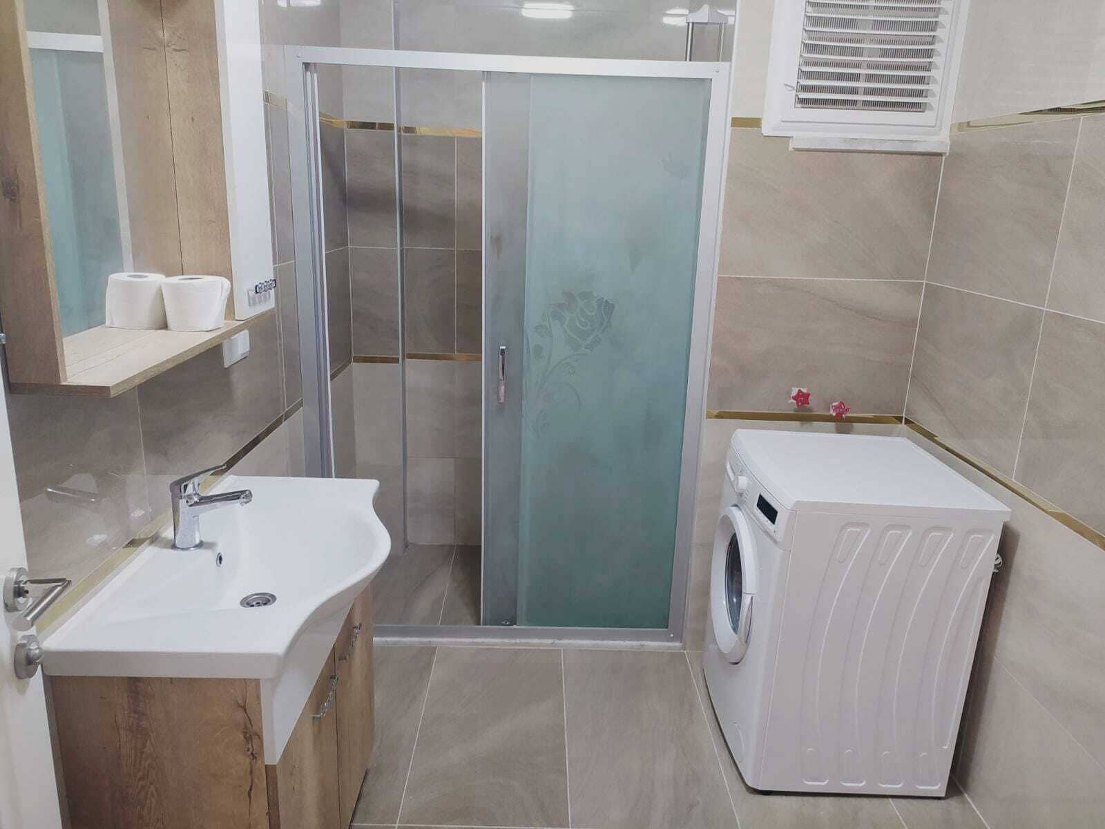 Un baño pequeño con lavamanos, inodoro y lavadora.