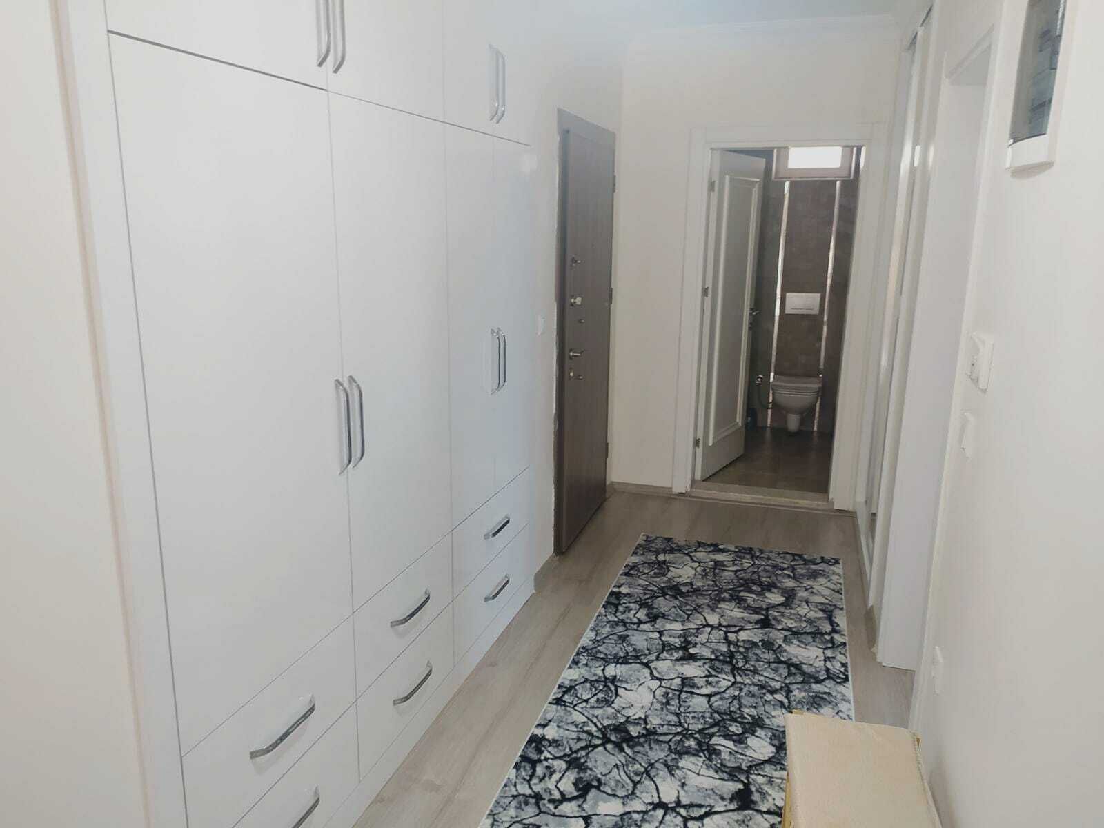 A narrow hallway with white wardrobes and a bathroom visible through an open door.